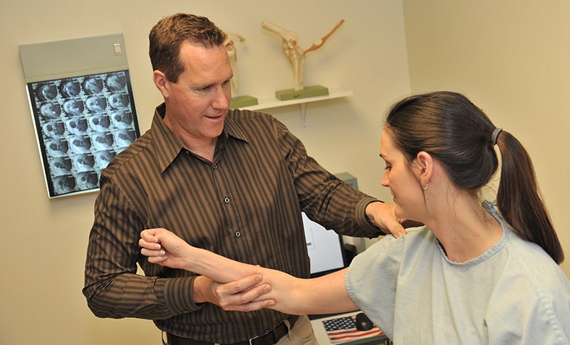 ortho doctor examining patient's shoulder for injury