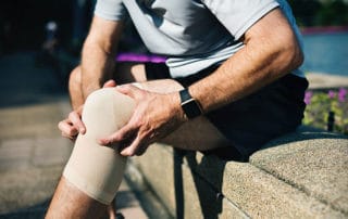 man with a knee brace holding his signifying knee pain