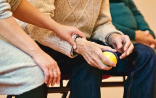 A group practices hand and wrist exercises under the guidance of a physical therapists