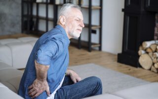 man holding his back experiencing winter joint pain