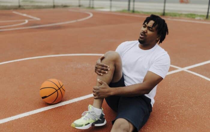 man sitting on basketball court with a torn ACL