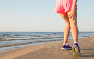 Female runner on the beach with pulled hamstring