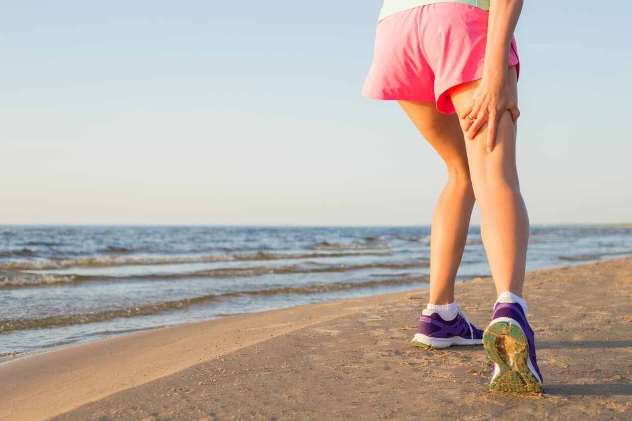 Female runner on the beach with pulled hamstring