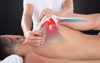 sports physical therapist Doing Treatment On Man's Shoulder