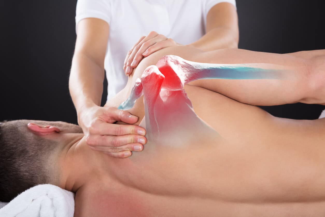 sports physical therapist Doing Treatment On Man's Shoulder