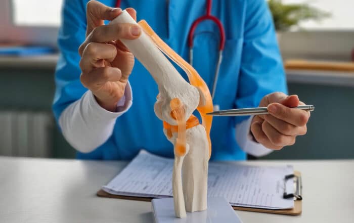 Doctor shows anatomy of structure of human knee joint to an ACL injury patient.