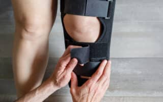 Image showing a female with knee Osteoarthritis in knee brace and doctor hands.