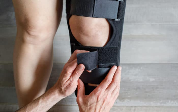 Image showing a female with knee Osteoarthritis in knee brace and doctor hands.