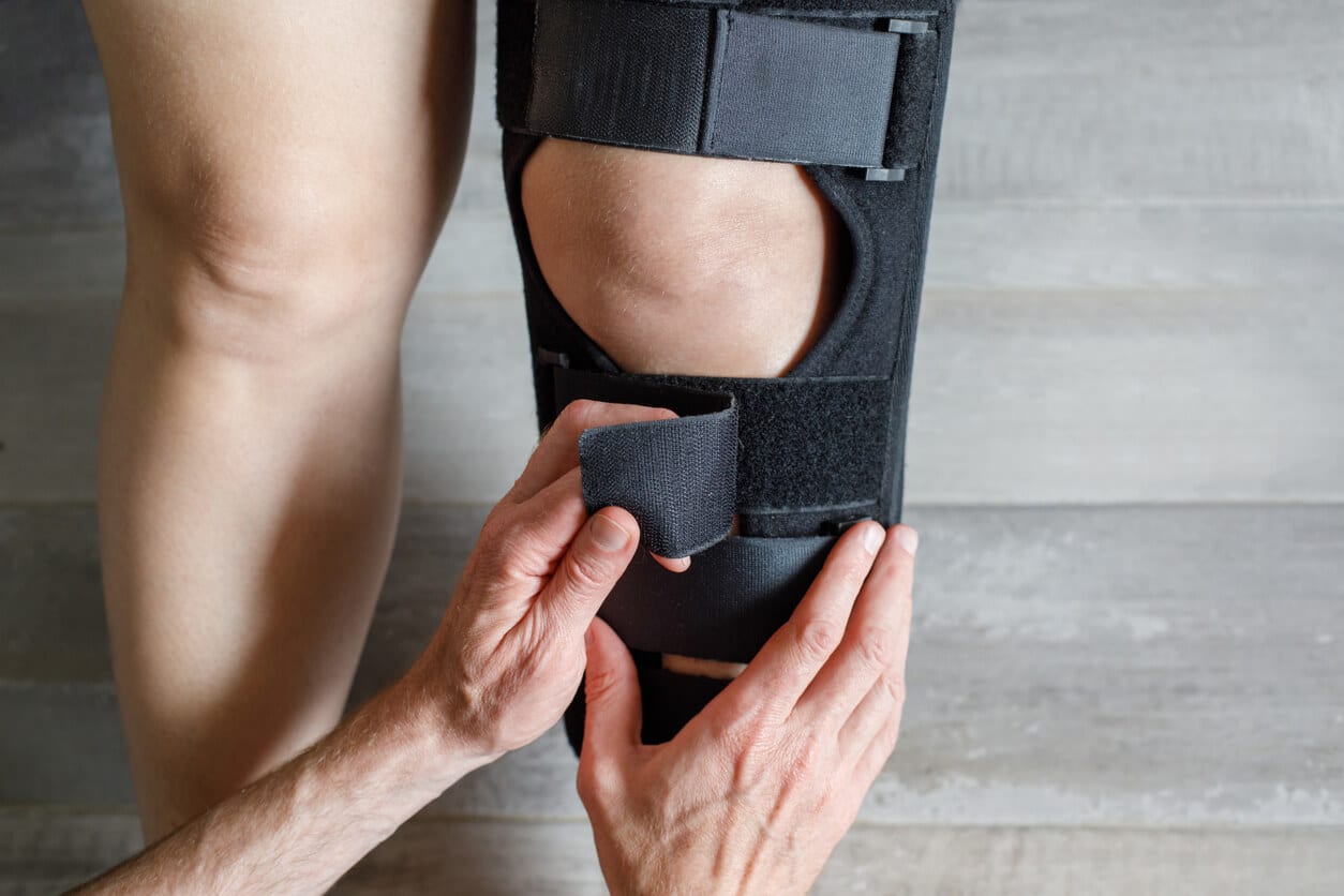 Image showing a female with knee Osteoarthritis in knee brace and doctor hands.