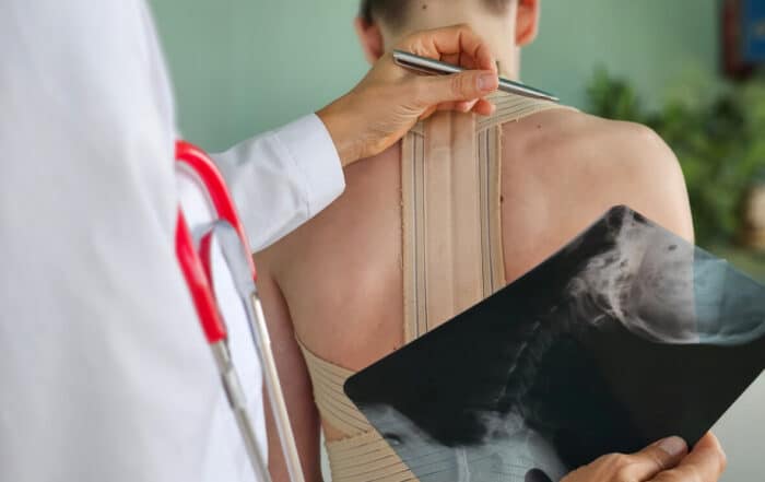 Doctor examining chronic spine patient back with x-ray of spine.