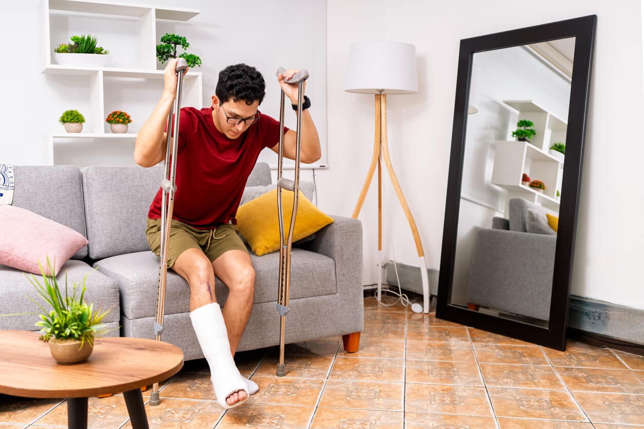Young man recovering from broken leg injury at home.