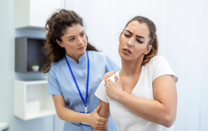 A woman in medical uniform fixing woman patients shoulder and back joints in manual therapy clinic during visit.